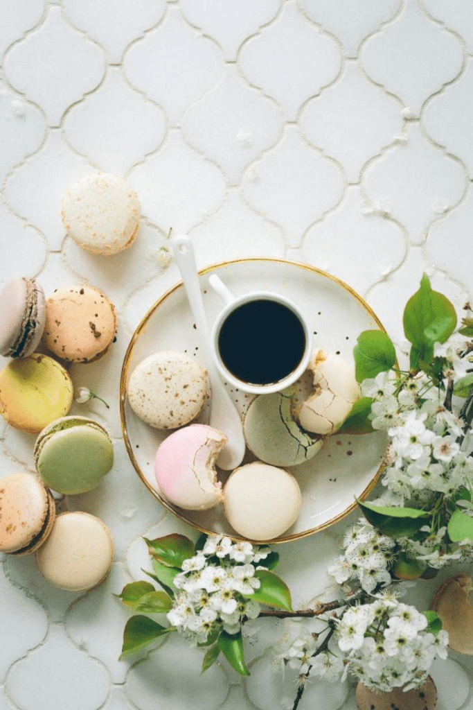 macarons and flowers laid out next to a small cup of tea