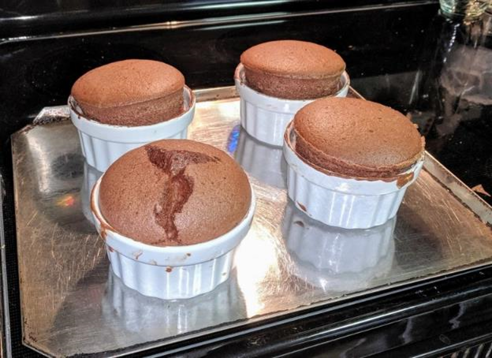 Chocolate souffles on a baking sheet.  One of them is cracked.